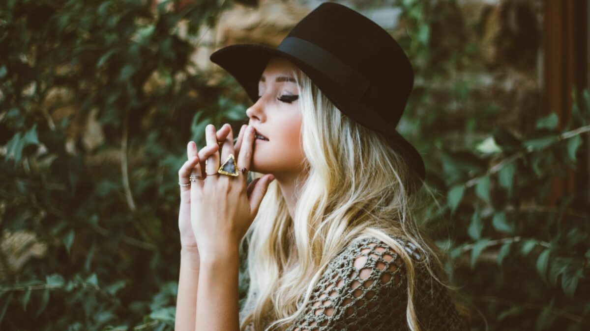 Blonde haired lady with black hat and rings on her fingers